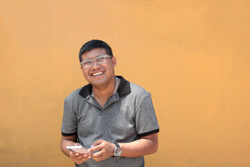 30-year-old dark-skinned Latino man with glasses uses his cell phone to work remotely, make calls,...