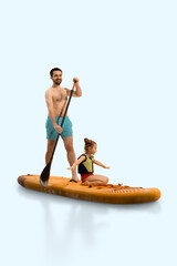 Joyful, smiling man, father standing on sup board, paddling with little girl daughter balancing...