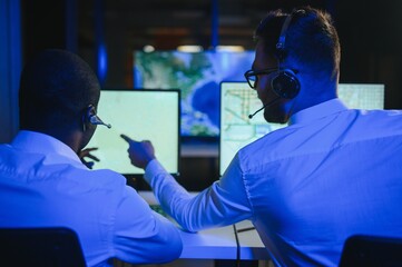 Center of dispatching maintenance. Portrait of men working via headset microphone while sitting on...