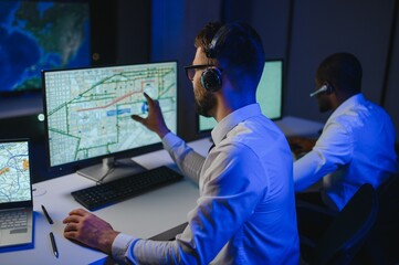 Center of dispatching maintenance. Portrait of men working via headset microphone while sitting on...