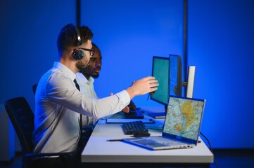 Center of dispatching maintenance. Portrait of men working via headset microphone while sitting on...
