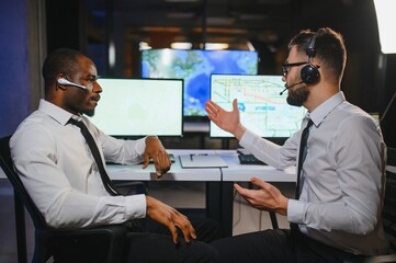 Center of dispatching maintenance. Portrait of men working via headset microphone while sitting on...