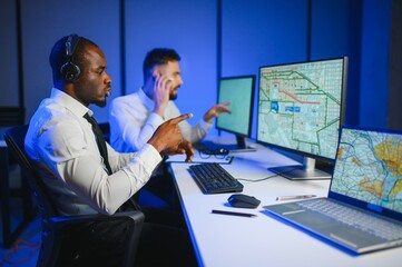 Center of dispatching maintenance. Portrait of men working via headset microphone while sitting on...