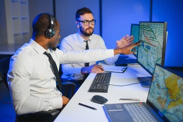 Center of dispatching maintenance. Portrait of men working via headset microphone while sitting on...