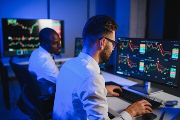 Conception of teamwork. Team of stockbrokers works in modern office with many display screens
