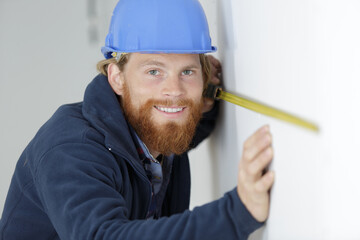 happy man measures on the wall with a ruler