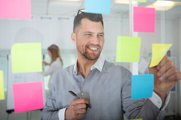 businessman removing sticky note reminder from window