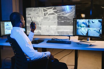 Serious African American security guard watching cctv video in surveillance room