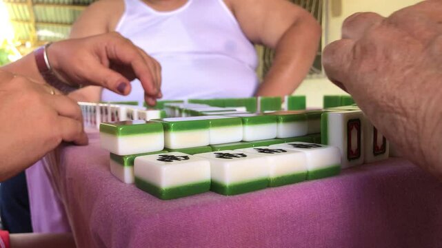 Family members are spending time playing the game of mahjong together at the table