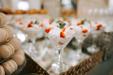Delicious dessert display featuring elegant glass cups filled with fresh strawberries and cream