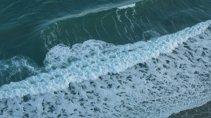 Aerial view of ocean waves crashing on shore white foam