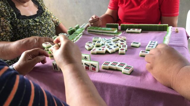 Family members are spending time playing the game of mahjong together at the table