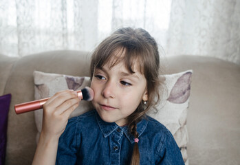 Mother putting makeup on her daughter face and they fool around together. Communication between women in the family. Fun time. Happy family concept. little girl doing her makeup