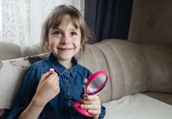 Mother putting makeup on her daughter face and they fool around together. Communication between women in the family. Fun time. Happy family concept. little girl doing her makeup