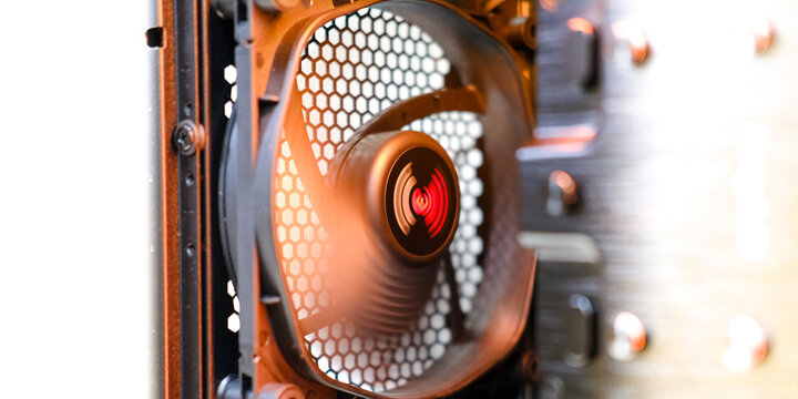 Computer cooling fan with intricate mesh design is spinning inside a modern PC case, showcasing advanced technology and efficient airflow for optimal performance