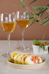 Farm cheese with salmon, olives and cream cheese in a plate with white non-alcoholic wine in glasses and green. Vertical orientation.