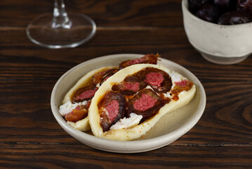 Slices of farm cheese roll with dates, freeze-dried strawberries and cream cheese with a glass of wine on a wooden table.
