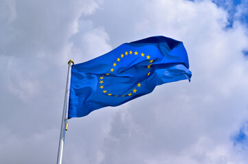 flag of the EU fluttering in the blue sky with cumulus clouds