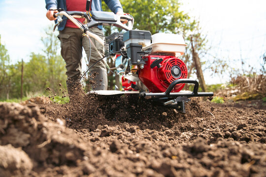 Farmer using tiller on a plowed field