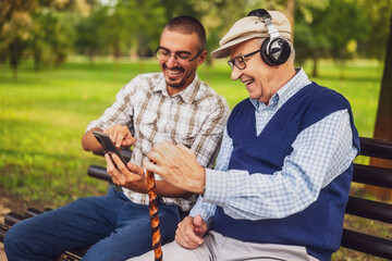 Portrait of happy grandfather and grandson in park. They are spending time together and having fun....