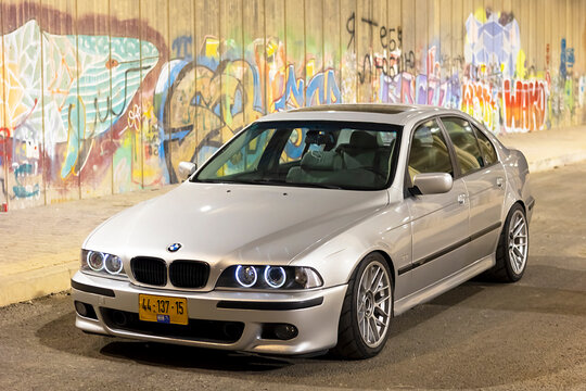 Rishon Lezion, Israel 22.08.2024. BMW M5 E39 parked on the street on a warm summer day against a wall with graffiti in the background.