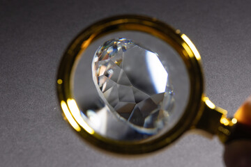 Diamonds in front of a dark background, reflections on the ground. brilliant cut diamond held by...