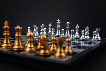 Golden and silver chess include king queen horse ship and pawn on dark background