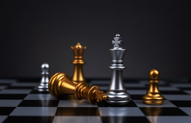 Silver king chess piece standing victorious over fallen golden king piece on chessboard. Concept of strategy,