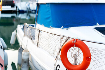Orange lifebuoy hanging on a moored boat with blue canopy
