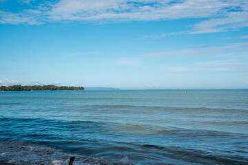 Tropical beach with calm blue sea, clear sky, and lush green island – perfect for travel, nature, and relaxation themes.