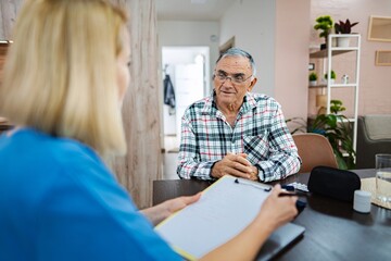 Elderly man chats thoughtfully with caregiver