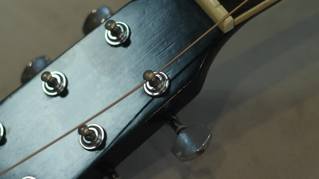 Close-up of installing new strings into guitar tuning pegs, string replacement process on an acoustic guitar