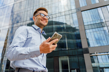 Young man enjoying a moment with smartphone in hand while standing outside a modern office building