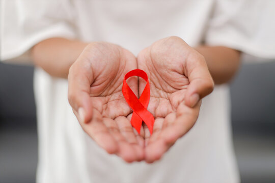 Hand Holding Red Ribbon for Supporting People Living and Illness. Cancer Awareness Month.