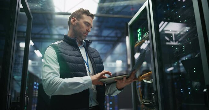 Focused Data Center IT Specialist Using Laptop Computer. System Administrator Working in a Server Farm Cloud Computing Facility, Setting Up Cybersecurity Network for Data Protection Service