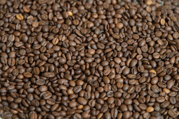 Dark roasted coffee beans are spread out on surface, showcasing their rich brown color and textured background. This display highlights the quality and variety of arabica or robusta beans. Copy space.