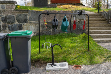 Water column with foot pump for water supply. Watering cans, shovels and other garden equipment in a public place for use by visitors to the church cemetery garden in Sweden. Garbage containers tanks.