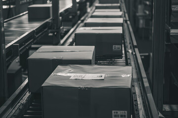 Conveyor belt with boxes on it. The boxes are black and white. The boxes are stacked on top of each other