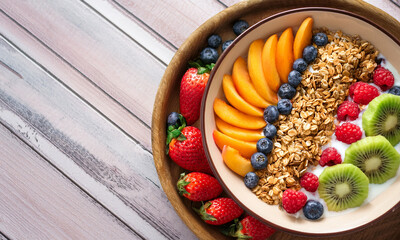 Top view of healthy breakfast with fresh fruits, granola, and yogurt on table in bright natural light, clean and minimal composition
