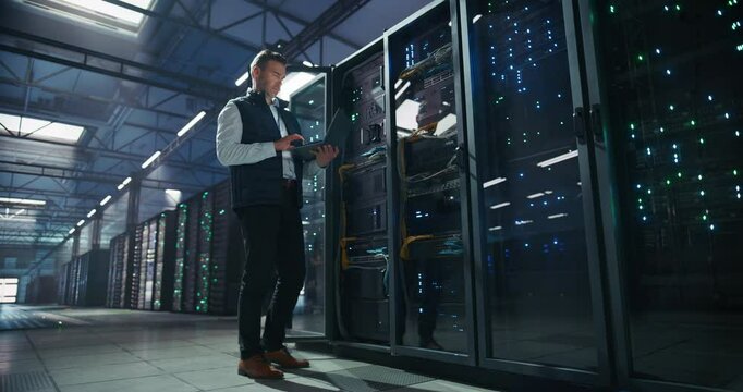 Data Center Administrator Using Laptop Computer. Maintenance Specialist Working on Cyber Security and Network Protection in AI Computing Facility. Engineer Checking Server Farm Analytics