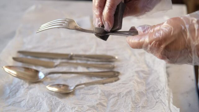 close-up of women's hands cleaning and polishing silverware, spoons, forks, knives