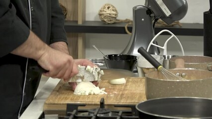 Cooking expert skillfully chops garlic and prepares ingredients in a stylish kitchen filled with essential cookware and tools. The focus is on precise technique and presentation