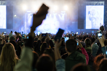 Streaming a music concert to social media via smartphone. audience waves at the night concert....