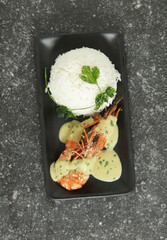 Delicious Fried Prawns with white Rice on a black rectangular plate with gravy top view