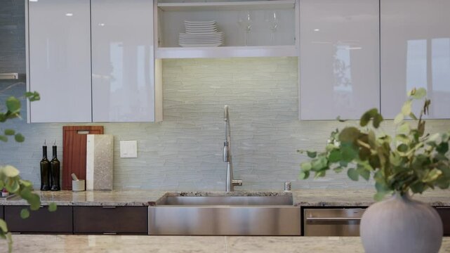 Orbiting shot of a modern kitchen sink with high-end finishes, backsplash tile, and clean decor