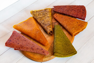 Assorted fruit pastille slices in different colors laid out in circular pattern on wooden board with soft background
