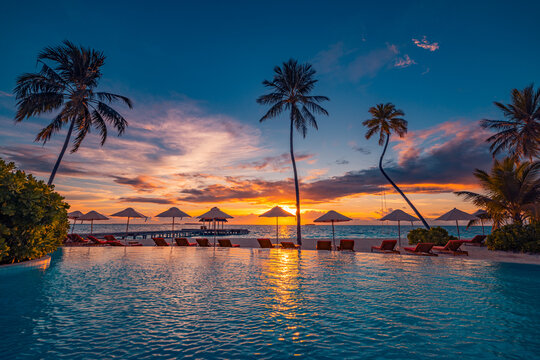 Golden sunset over tranquil beach resort pool palm trees, reflecting warm sunlight on water and seascape. Idyllic tropical escape for relaxation luxury tourism resort vacation. Summer calm landscape