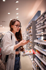 Woman Comparing Art Supplies with Phone in Store