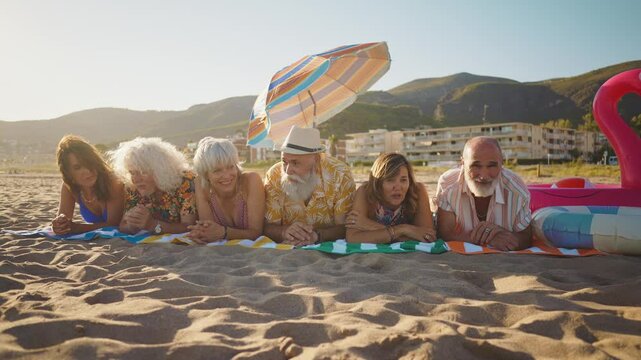 Happy senior people at the beach joyful senior friends are gathering around a charismatic man with long white hair, laughing and embracing on a sunny beach