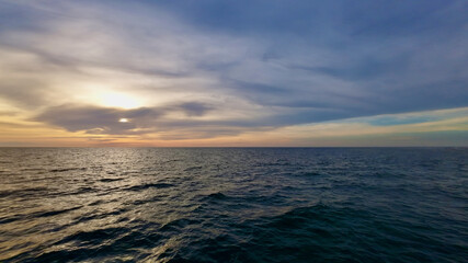 Obraz premium Picturesque sunset over the sea. View of the calm surface of the sea and clouds above the horizon during sunset.
